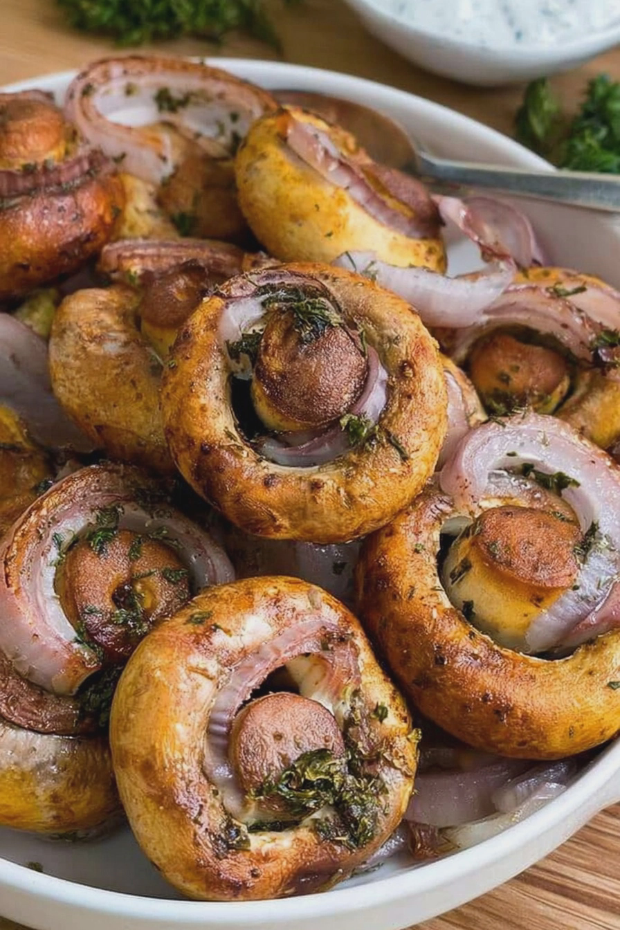 Gebackene Champignons aus der Heißluftfritteuse serviert mit Knoblauchsoße und Kräutern.