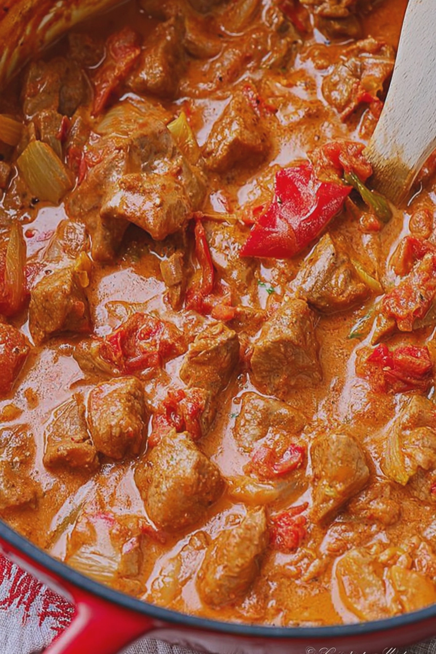 Frischer Party Pfundstopf aus dem Ofen, serviert in einem großen Bräter mit Zwiebeln und Paprika.